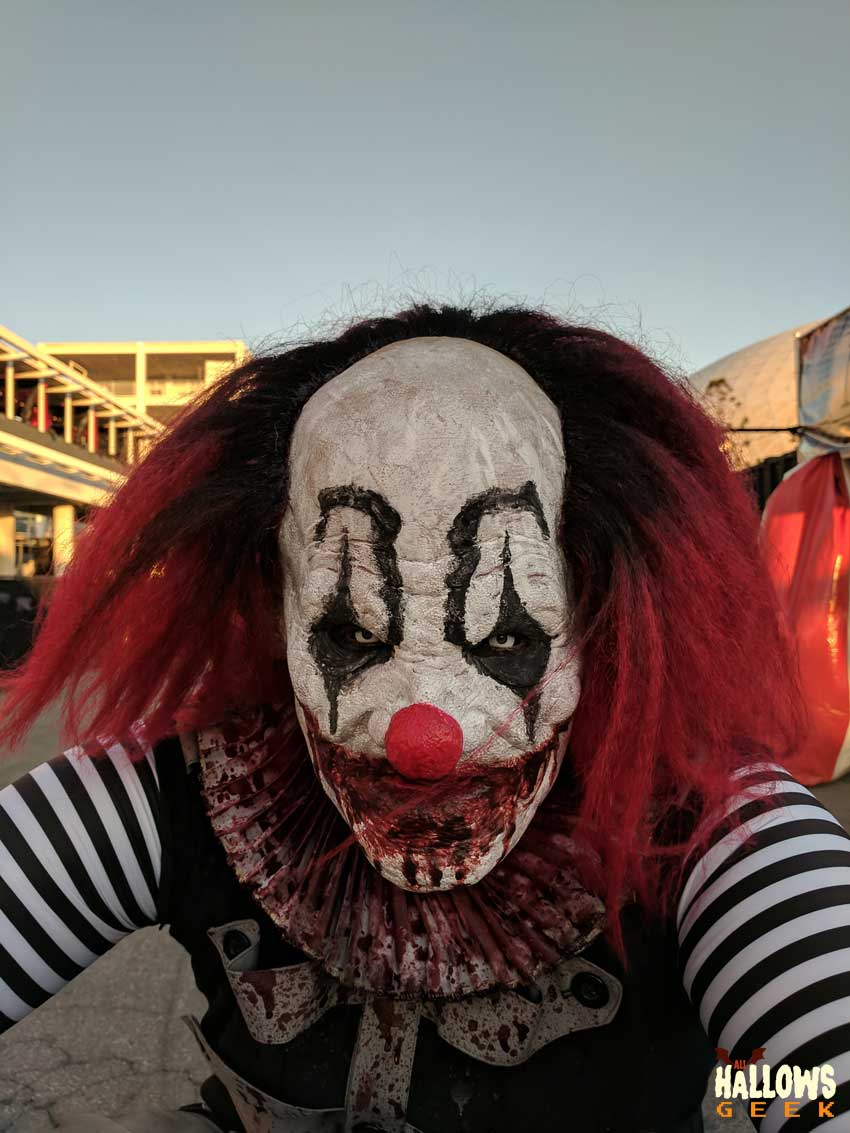 A Clown on stilts kneels down for a photo opp at The Queen Mary's Dark Harbor