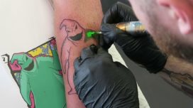 Tattoo artist tattooing The Nightmare Before Christmas' Oogie Boogie on a persons arm