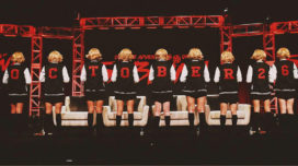 Women dressed as Sabrina wearing varsity jackets that spell out October 26