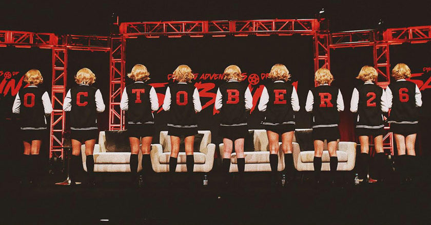 Women dressed as Sabrina wearing varsity jackets that spell out October 26