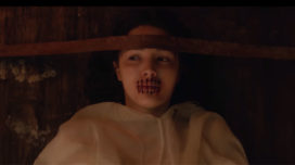 Lore Season 2 still of girl strapped to a table with her mouth sewn shut
