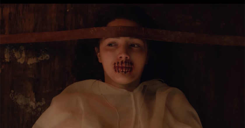 Lore Season 2 still of girl strapped to a table with her mouth sewn shut