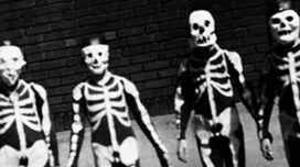A black and white photo of four kids wearing vintage skeleton costumes