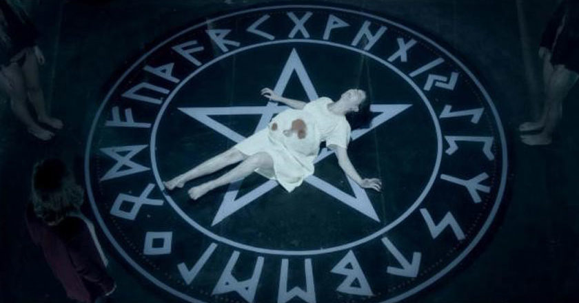 A pregnant woman lies in the middle of a giant pentagram in a still from 'Luciferina'