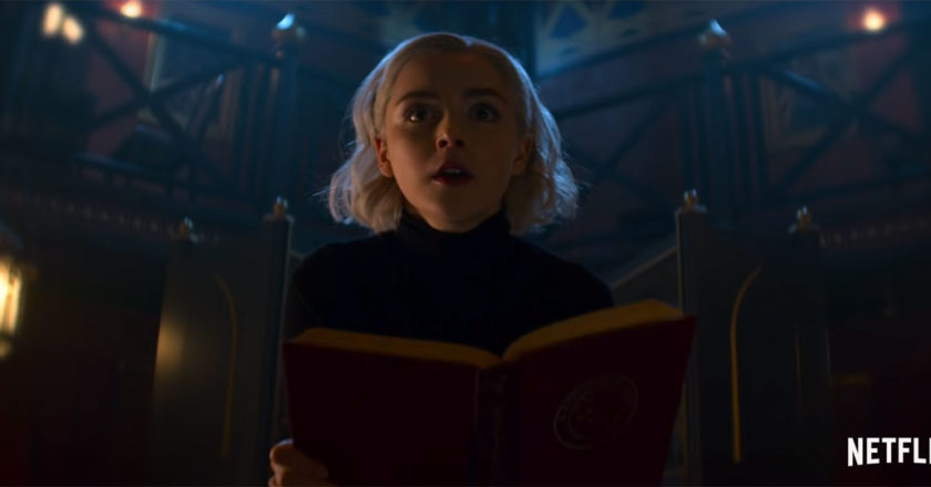 Sabrina Spellman holding a spell book in a dark room from the Chilling Adventures of Sabrina: Part 2 teaser