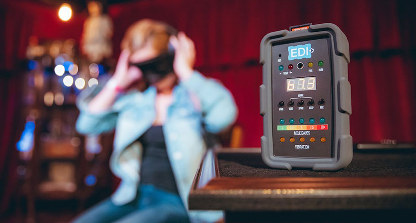 A blindfolded woman and paranormal investigation equipment