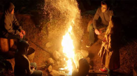 Members of The Midnight Society sit around a campfire