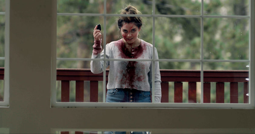Gracie Gillam stands outside a window covered in blood in Superhost