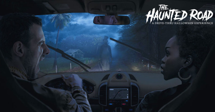 The Haunted Road key art featuring a man and woman in a car with a ghost in a top hat standing in front of them in the road