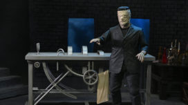 NECA's Ultimate Frankenstein Figure with bandaged head standing in front of lab table accessory