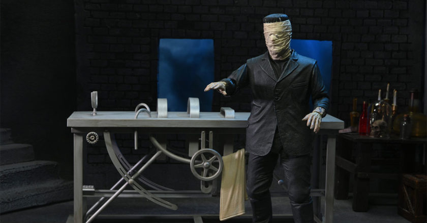 NECA's Ultimate Frankenstein Figure with bandaged head standing in front of lab table accessory