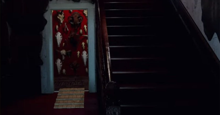 Screenshot from the "The Texas Chain Saw Massacre" video game showing the red room of skulls next to the staircase