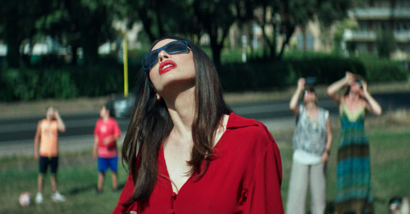 Ilenia Pastorelli looks up at an eclipse while wearing dark sunglasses in "Dark Glasses"