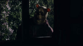 Winnie-the-Pooh looks through a window at night