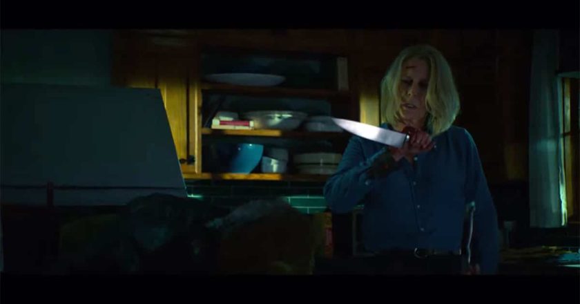 Jamie Lee Curtis as Laurie Strode holds a knife over the hunched over body of Michael Myers