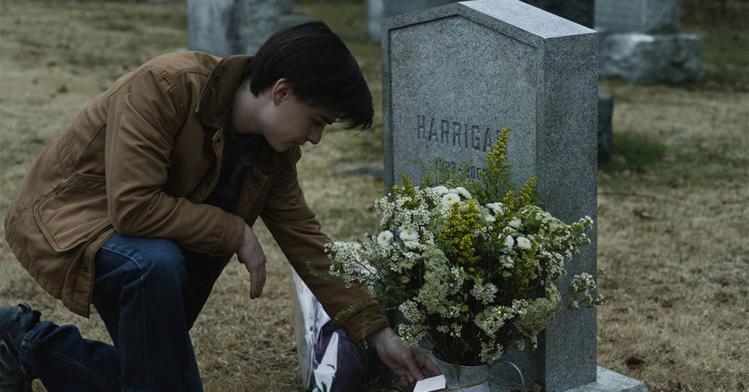 Jaden Martell as Craig in "Mr. Harrigan's Phone" kneels over the grave of Mr. Harrigan.