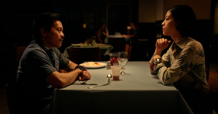 West Liang as Elliot and Amy Tsang as Greta sit at a restaurant table in "Silent River"