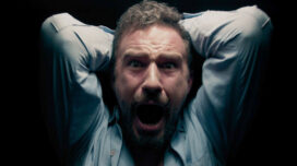 Brian Moore screams with his arms raised above his head in a dark room in "The Sleep Experiment"
