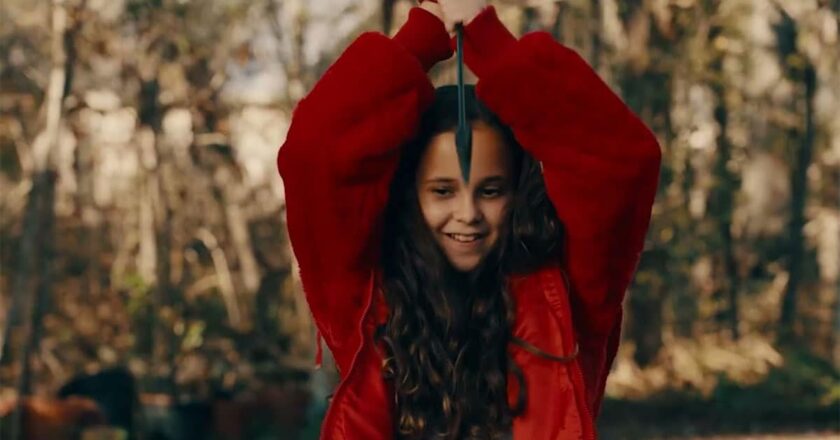 Briella Guiza holds an arrow above her head in the trailer for "There's Something Wrong With The Children."