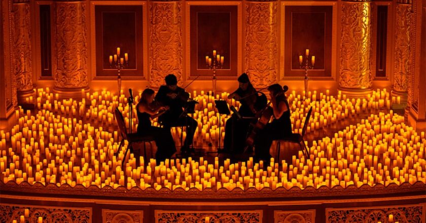 A string quartet performs amidst a stage filled with lit candles.
