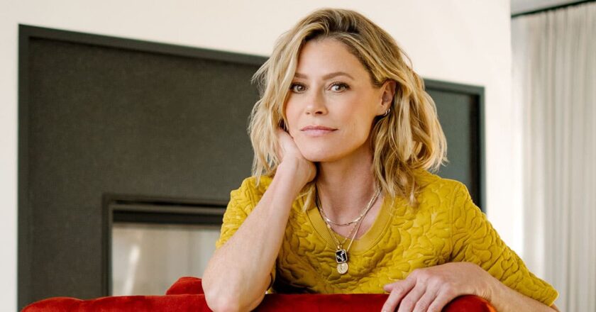 Julie Bowen sitting on a red couch.