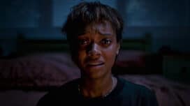 Sophia Wilde sits at the end of a bed with a scared look on her face in "Talk to Me"