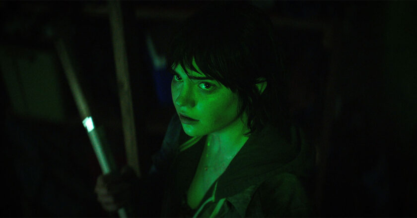 Sophie Thatcher lit by green light in a dark room in "The Boogeyman"