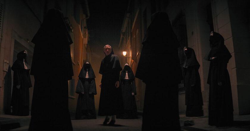 Still from the Nun 2 featuring Sister Irene surrounded by dark nuns