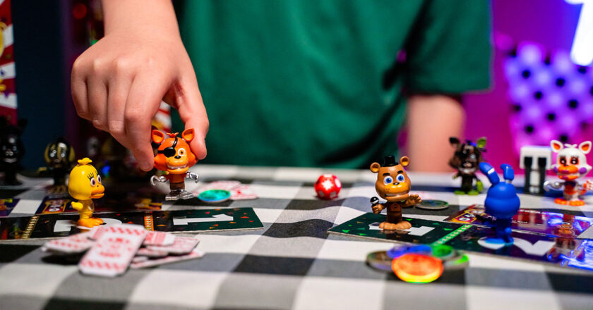 A kid places his Foxy game character on a game piece in Five Nights At Freddy's Fightline