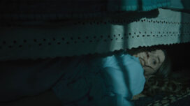 Kaitlyn Dever as Brynn, hides under a bed in a moonlit room.