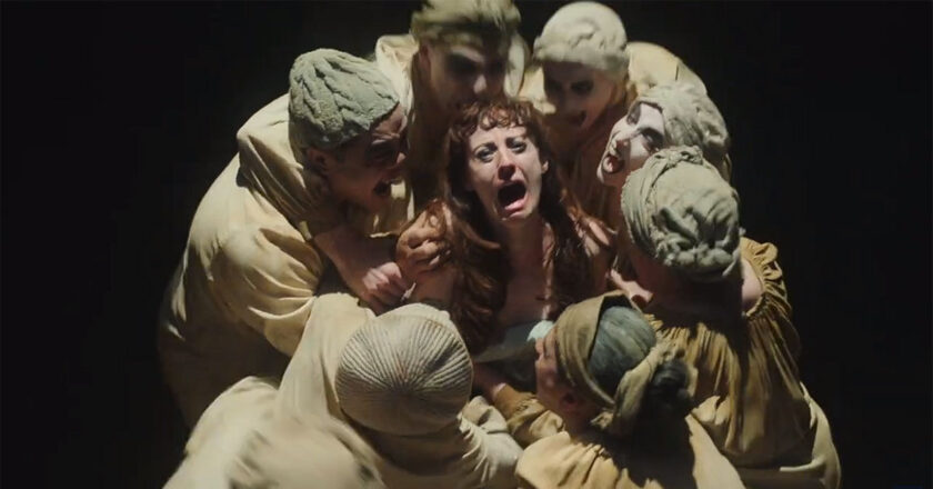 A stage actress looks up in terror as she is surrounded by vampires at the Theatre Des Vampires