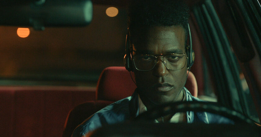 Luke James as Edmund sits in a car with headphones on in "THEM: The Scare"