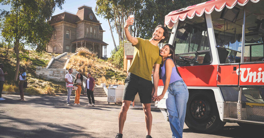 A couple poses next to a Glamour Tram in front of the Psycho House