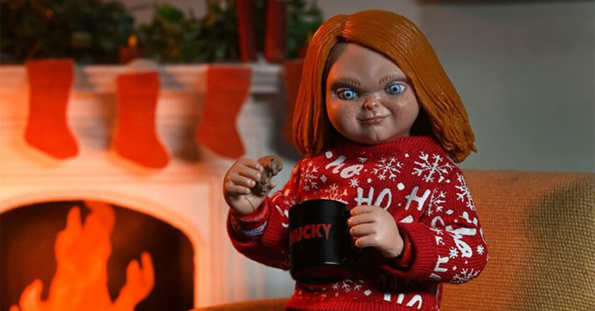 Ultimate Chucky Holiday Edition in Ho-ho-ho-holiday sweater holding a cookie and Chucky mug