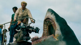 Director Steven Spielberg, kneeling with camera, during production of JAWS